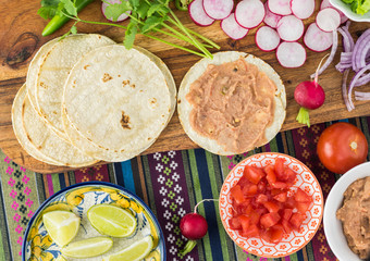 Ingredients for homemade vegetarian corn tacos with refried beans and vegetables.