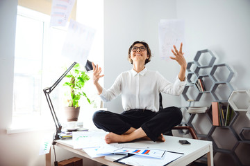 Obraz premium Young beautiful businesswoman throwing up papers, sitting on table.
