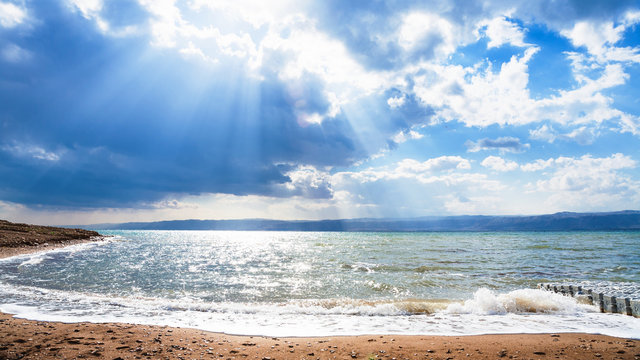 sunbeams passes through blue clouds over Dead Sea
