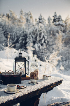 Cup of coffee and biscuits on snow covered picnic bench 