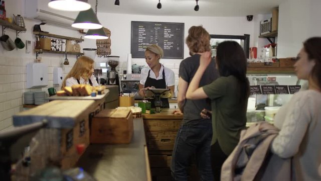  Cheerful worker serving customers & taking payment in city coffee shop