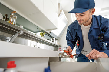 Smiling handyman repairing water pipes