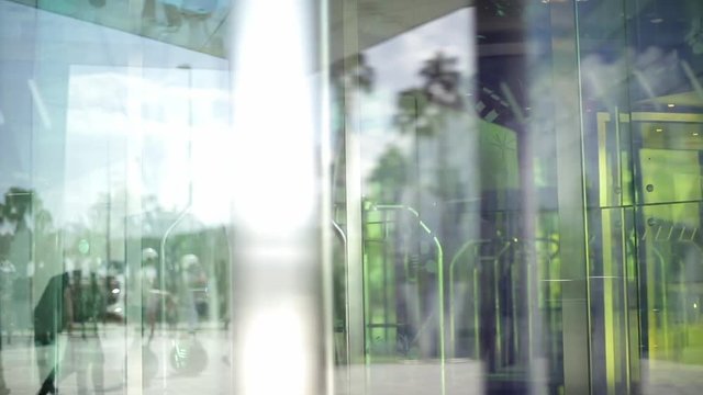 People using automatic revolving glass door or entering rotating spinning glass doorway. Entrance to the hotel,business ,exhibition or shopping center. People silhouettes and their reflection.
