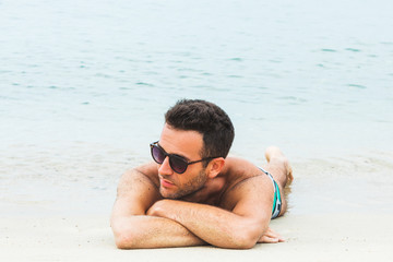 Handsome young man sunbathing on the beach