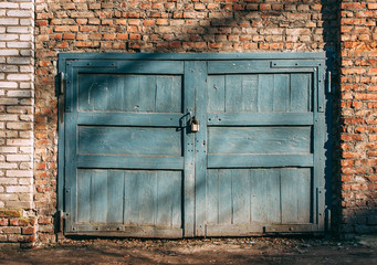 Old garage gates with padlock and brick wall. © schekochihin