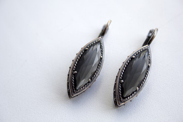 Silver earrings with a black gem on a white background