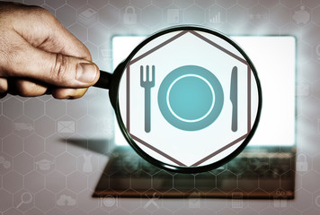 Hand holds the magnifying glass in front of an open notebook. Among the many icons, attention is...