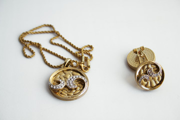 Gold plated earrings and pendant on a white background