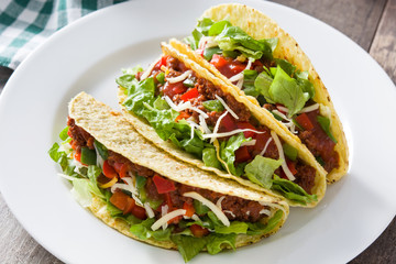 Traditional Mexican tacos with meat and vegetables on wooden background
