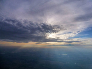 Fototapeta na wymiar Sun breaking out behind clouds, seen from a plane window