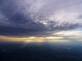 Naklejka na ściany i meble Sun breaking out behind clouds, seen from a plane window