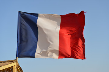 French flag waving in the wind against the blue sky