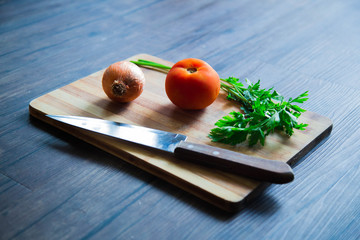 Fresh organic gourmet onion tomato parsley on light wood board and dark wood