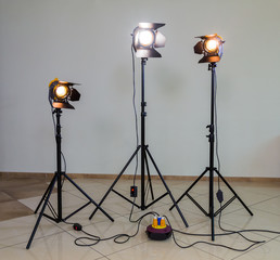 Three halogen spotlights with Fresnel lenses on a grey background. Photographing and filming in the...
