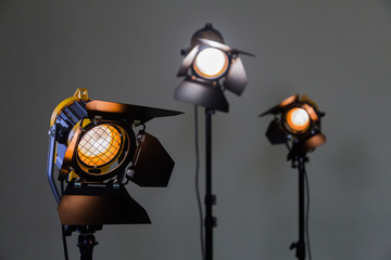 Three halogen spotlights with Fresnel lenses on a grey background. Photographing and filming in the...