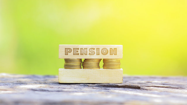 Business Concept -PENSION WORD, Golden coin stacked with wooden bar on shallow DOF green background