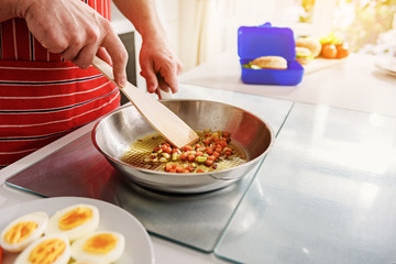 Male arms preparing breakfast on frying pan