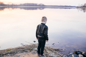 Little boy stands near the water at sunset. Conceptual photo
- 143073496