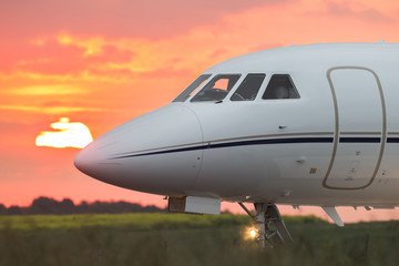 Fototapeta na wymiar Nose of a private business jet on the runway with the sun in the background