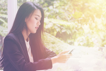 Happy young business woman sitting at urban cafe with coffee ,using her smart phone