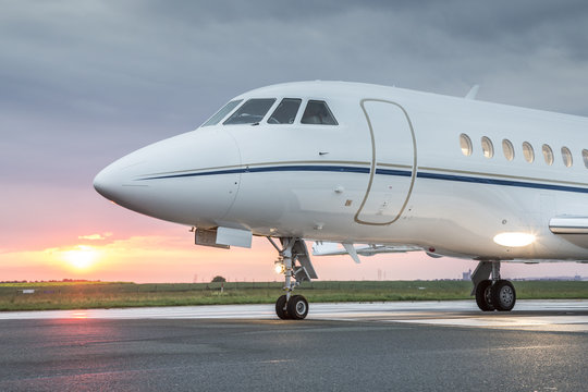 Large private business jet on runway, ready for takeoff, during sunrise