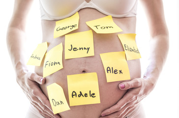 Pregnant woman holding her belly with names on paper stickers, isolated on white background