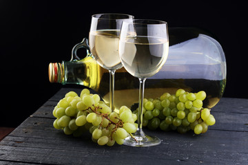 Bottle and glass of white wine, grape on wooden table