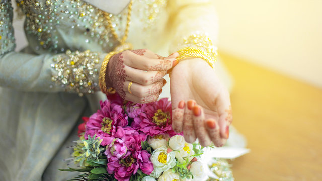 graceful poses of girls hand wearing gold bangles, with beatiful flower, selective focus shallow DOF.