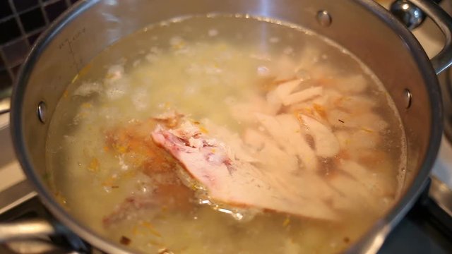 Bubbling meat soup, inside a metal pot, at a restaurant kitchen