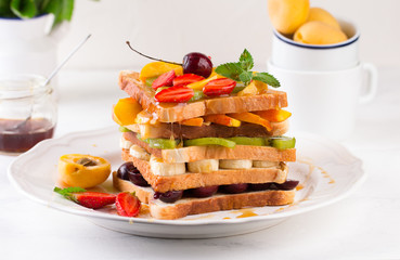 Creative healthy burger filled with sliced fresh tropical fruits, strawberries and cherry. Healthy eating concept