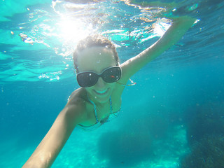 Naklejka premium Underwater shoot of a woman swimming over sandy sea bottom