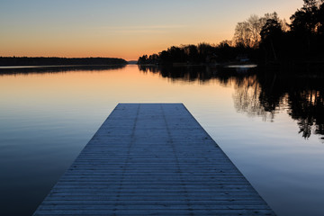 Jetty in early morning sunrise in winter landscape in sweden