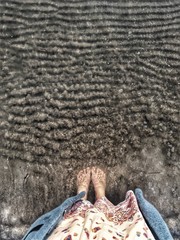 Female feet standing in clean water of Adriatic sea beach in early spring in Albania