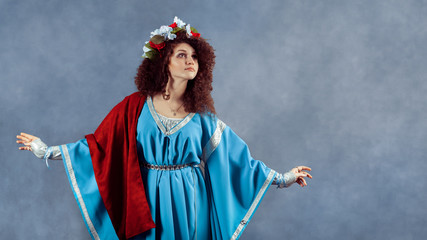 Fototapeta premium Beautiful princess with colorful wreath of flowers in her curly head.