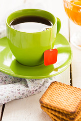 Black tea in green cup with cookies and apricot jam