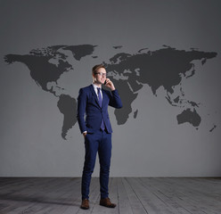 Businessman standing with smartphone. World map background. Business, globalization, concept.