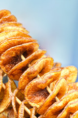 The potatoes on the skewer close-up on blue background. Trade in the street in the summer.
