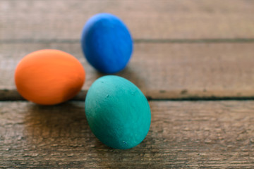 Multi-colored Easter eggs on a wooden background in the nest.