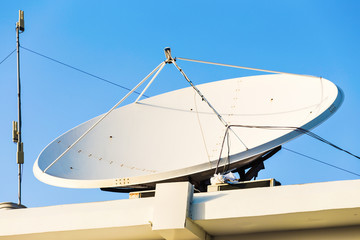 satellite dish and TV antennas on the house roof with blue sky background