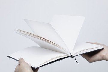 Opened notebook with white pages close-up in the women's hands on a white background