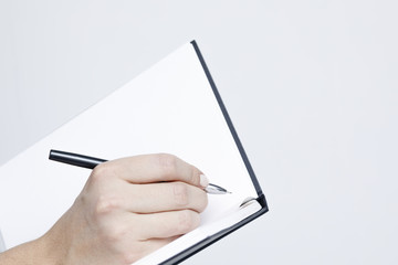Notebook with a pen close-up in the women's hands on a white background