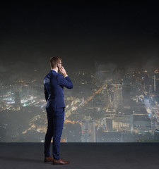 Businessman with smartphone standing on a night city background.  Job, business, career, concept.