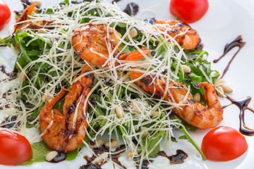 Salad with shrimps and cheese on a white plate
