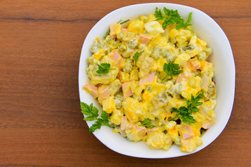 Russian traditional salad olivier on wooden table