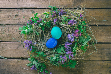 Multi-colored Easter eggs on a wooden background in the nest.