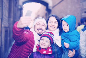 Happy family of four doing selfie in city