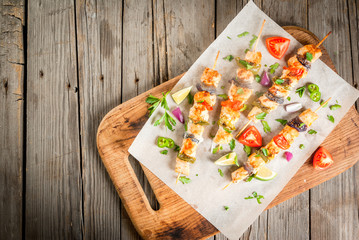 Fajita chicken kebabs, with chicken meat, pepper, chili, tomatoes, onions, lime juice and herbs. In a frying pan, on a rustic wooden table. Mexican cuisine, a traditional food,