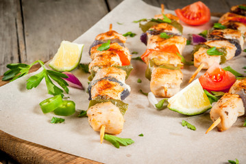Fajita chicken kebabs, with chicken meat, pepper, chili, tomatoes, onions, lime juice and herbs. In a frying pan, on a rustic wooden table. Mexican cuisine, a traditional food,
