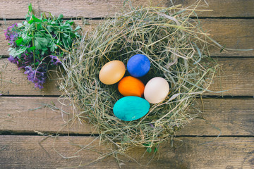 Multi-colored Easter eggs on a wooden background in the nest.
