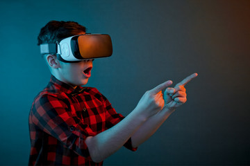 Boy in VR headset pointing on side